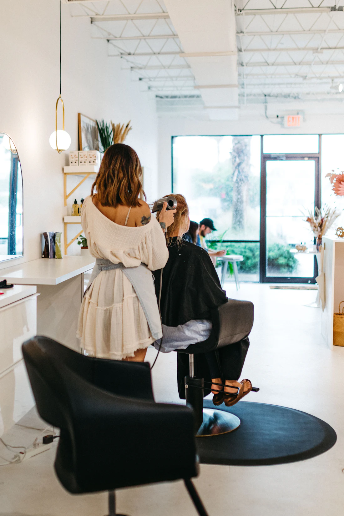 Inside the studio — a stylist finishing a client in a bright, airy salon